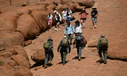 Des touristes font l'ascension du rocher d'Uluru une derniĂšre fois avant son interdiction, le 25 octobre 2019 au Parc national Uluru-Kata, en Australie