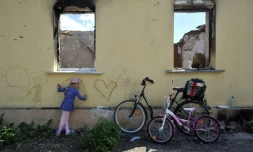 Une jeune fille dessine sur le mur d'une maison détruite à Andriivka, dans la région de Kiev, le 3 juin 2022
