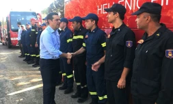 Le Premier ministre grec Alexis Tsipras (c) salue les pompiers ayant combattu les incendies meurtriers de Mati, à l'est d'Athènes, le 30 juillet 2018