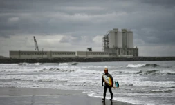 Koji Suzuki, un surfeur japonais, marche sur la plage de Minamisoma devant une centrale thermique, à une trentaine de km au nord de la centrale nucléaire de Fukushima Daiichi, le 4 mars 2020 