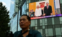 Un homme passe à Pékin devant un écran montrant la rencontre entre la cheffe du gouvernement italien Giorgia Meloni et le président chinois Xi Jinping le 28 juillet 2024