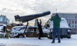 Une femme pose sur fond d'un drone russe Shahed abattu et exposé à Kiev, le 17 février 2026