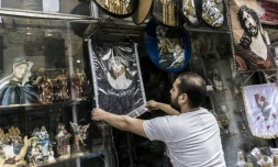 Un vendeur égyptien accroche une image du Christ à l'extérieur de sa boutique d'objets et de bibelots religieux, le 11 avril 2017 dans le quartier de la Choubra, au Caire