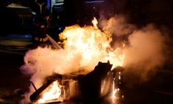 Un pompier éteint l'incendie d'une poubelle aprÚs des affrontements entre des manifestants et la police le 25 mars 2018 à Barcelone