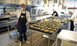 Eric Ripert, chef et co-propriétaire du restaurant étoilé new-yorkais Le Bernardin, avec deux employés préparant des repas en barquettes pour des soignants, le 6 mai 2020 à New York
