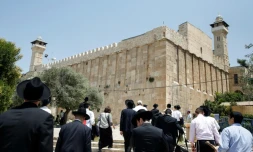 Des religieux juifs et des touristes marchent vers le Tombeau des Patriarches, également appelé Mosquée d'Ibrahim, à Hebron, le 7 juillet