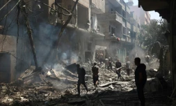 Des Palestiniens marchent le 8 juin 2024 dans des gravats de bâtiments détruits lors d'une opération israélienne pour libérer des otages à Nousseirat, dans le centre de la bande de Gaza, où une guerre oppose Israël au mouvement islamiste Hamas