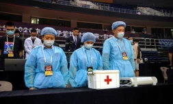 Du personnel soignant rend hommages aux morts du coronavirus avant un match de basketball Ă Qingdao, le 20 juin 2020