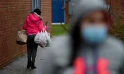 Un passant porte de la nourriture récupérée auprÚs d'un centre de charité, à Baltimore, le 4 décembre 2020