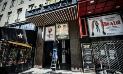 Des employés retirent d'anciennes affiches sur la devanture du cinéma Max Linter à Paris, le 18 juin 2020