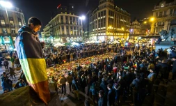 Un homme enveloppé dans un drapeau belge tient une bougie place de la Bourse, à Bruxelles, le 24 mars 2016, en hommage aux victimes des attentats de l'aéroport de Zaventem et du métro bruxellois