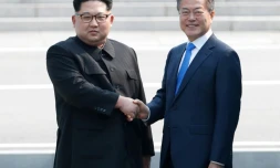 Moon Jae-in (d) et Kim Jong Un se serrent la main sur la ligne de démarcation avant le début du sommet, le 27 avril 2018 à Panmunjom