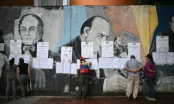 Des électeurs regardent les listes électorales devant un bureau de vote à Caracas, lors des élections pour élire députés et gouverneurs, le 25 mai 2025 au Venezuela