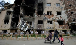 Une femme et sa fille passent devant un immeuble détruit à Irpin, près de Kiev, le 16 juin 2022