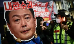 Un manifestant brandit un portrait du président sud-coréen Yoon Suk Yeol, lors d'un rassemblement pour sa démission, le 8 décembre 2024 à Séoul