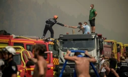 Un pompier tend un masque à un volontaire en pleine lutte contre un feu de forêt à Lanton, à l'est du bassin d'Arcachon et à l'ouest de Bordeaux, le 29 juillet 2026