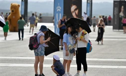 Des touristes se protĂšgent du soleil avec des ombrelles, le 18 juillet 2023 Ă Madrid, pendant une vague de chaleur en Espagne