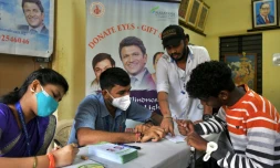 Le personnel de l'hôpital ophtalmologique Narayana Nethralaya aide un volontaire à remplir un formulaire de don des yeux lors d'un événement à la mémoire de l'acteur Puneeth Rajkumar à Bangalore le 18 novembre 2021