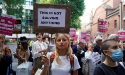Une manifestante contre les expulsions de migrants du Royaume-Uni vers le Rwanda brandit une pancarte où il est écrit "Cela ne résoudra rien", devant le ministère britannique de l'Intérieur à Londres, le 13 juin 2022 