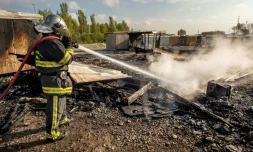Un pompier arrose les décombres de maisons détruites par un incendie dû à des rixes entre Afghans et Kurdes dans le camp de migrants de Grande-Synthe le 11 avril 2017 à Dunkerque