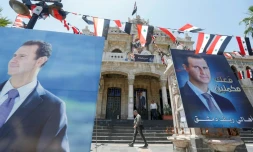 Des passants passent devant des affiches électorales de Bachar al-Assad, le 25 mai 2021 à Damas.