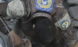 Un volontaire de la défense civile syrienne dégage un garçon coincé dans les décombres d'un immeuble, le 25 juillet 2016 à Alep, dans le nord de la Syrie