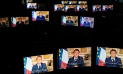 Emmanuel Macron sur des écrans de tablette alors qu'il parle depuis l'Elysée lors d'une allocution télévisée, le 13 avril 2020 à Paris

