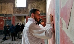 Photo prise le 18 février 2020 montrant un restaurateur nettoyant une fresque de "La maison des chastes amants" à Pompéi