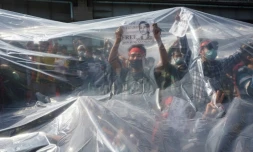 photo prise le 9 février 2021 montrant des manifestants en Birmanie sous un plastique les protégeant des canons à eau de la police à Rangoun