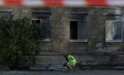 Un policier ukrainien inspecte des débris près d'un bâtiment endommagé par une frappe de drone russe à Kiev, le 1er octobre 2026