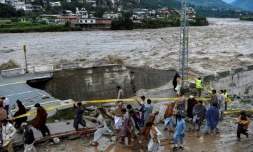 Des personnes se rassemblent devant une route endommagée par inondations consécutives aux fortes pluies de mousson dans la vallée de Swat, dans le nord du Pakistan, le 27 août 2022