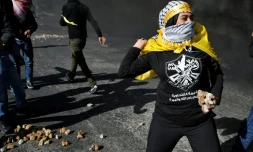 Une Palestinienne jette des pierres aux soldats israéliens à Ramallah, le 11 décembre 2017, pour protester contre la décision américaine de reconnaître Jérusalem comme capitale d'Israël