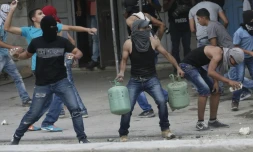 De jeunes palestiniens lancent des pierres contre les forces de sécurité israéliennes au checkpoint de Qalandia entre Jérusalem et Ramallah, le 6 octobre 2015