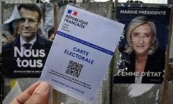 Une carte électorale devant des affiches de la candidate du parti d'extrême droite Rassemblement National, Marine Le Pen (D), et du président sortant et candidat à sa réélection, Emmanuel Macron (G), à Montpellier, dans le sud de la France, le 21 avril 2022