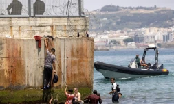 Des policiers espagnoles tentent de disperser des migrants qui arrivent Ă l'enclave espagnole de Ceuta, le 18 mai 2021 Ă Fnideq
