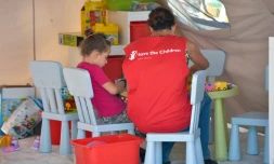 Un membre de l'ONG Save the Children près d'un enfant dans un campement à Amatrice le 27 août 2016