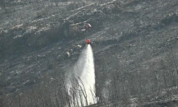 Un hélicoptère de la Sécurité civile déverse sa cargaison d'eau près du village de Coustouge, dans l'Aude touchée par des incendies, le 8 août 2025 
