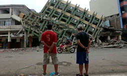 Deux hommes regardent un immeuble détruit à Portoviejo, en Equateur, le 21 avril 2016, une semaine après le violent séisme qui a ravagé le pays
