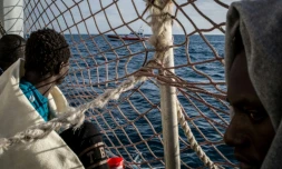 Des migrants à bord du Sea Watch 3 observent un bateau des garde-côtes italiens
