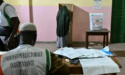 Une personne vote lors des élections législatives en Côte d'Ivoire, sous la surveillance d"un membre de la commission électorale indépendante, à  Abidjan le 27 décembre 2025