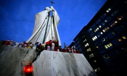 Des fleurs et des bougies déposées au pied d'une statue de Jean-Paul II devant l'hôpital Gemelli où est hospitalisé le pape François, le 20 février 2025 à Rome