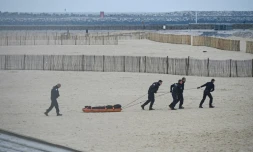 Des agents de police Ă©vacuent un corps dĂ©couvert sur la plage de Calais, d'oĂč de nombreux migrants tentent la pĂ©rilleuse traversĂ©e de la Manche, le 6 novembre 2024