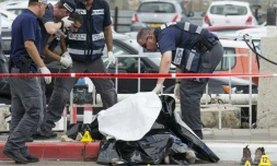 Les forces de sécurité israéliennes inspectent le corps d'un Palestinien abattu après avoir agressé au couteau une soldate israélienne et trois passants dans la ville côtière de Tel Aviv, en Israël, le 8 octobre 2015