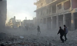 Des Syriens courent dans les débris de la ville de Binnish près d'Idleb après un raid aérien, le 12 janvier 2017