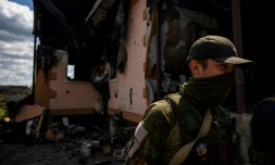 Un médecin de la garde nationale, passe devant une maison incendiée à Kharkiv, dans l'est de l'Ukraine, le 20 mai 2022