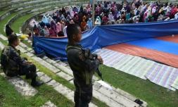 Des membres des forces spéciales de police montent la garde pendant que des musulmanes qui ont fui les combats à Marawi entre les forces armées philippines et les islamistes prient lors de l'Aïd el-Fitr à Iligan, sur l'île de Mindanao, le 25 juin 2017