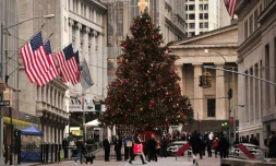 Des gens passent devant un arbre de Noël devant le New York Stock Exchange à New York, le 24 décembre 2013
