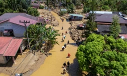 Cette photo aérienne montre des villageois pataugeant dans la coulée de boue pour trouver un abri après les crues soudaines du village de Tukka, dans le district de Tapanuli central, province de Sumatra du Nord, le 3 décembre 2025