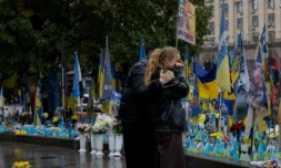 Des passants devant un mémorial improvisé pour les soldats ukrainiens et étrangers morts au combat, le 7 octobre 2025 à Kiev 
