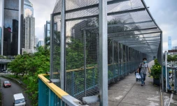 Un habitant de Hong Kong emprunte le 3 juin 2020 une passerelle recouverte de grillage, édifiée par les autorités locales en réponse aux manifestations pro-démocratie.